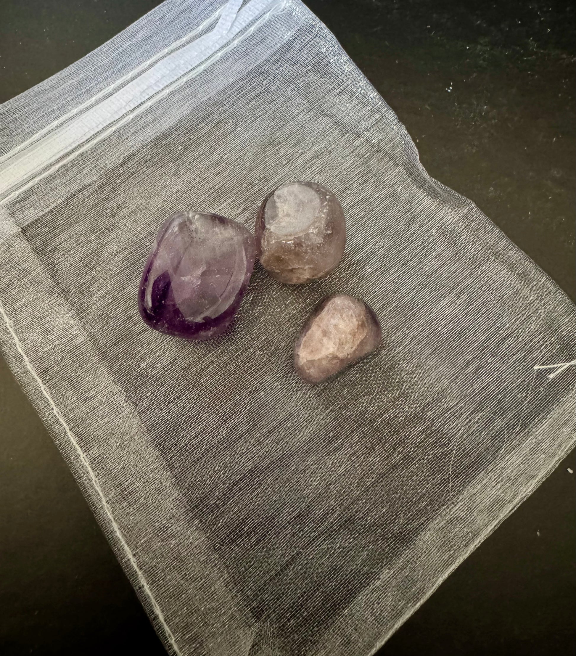 Three amethyst crystals on a textured surface