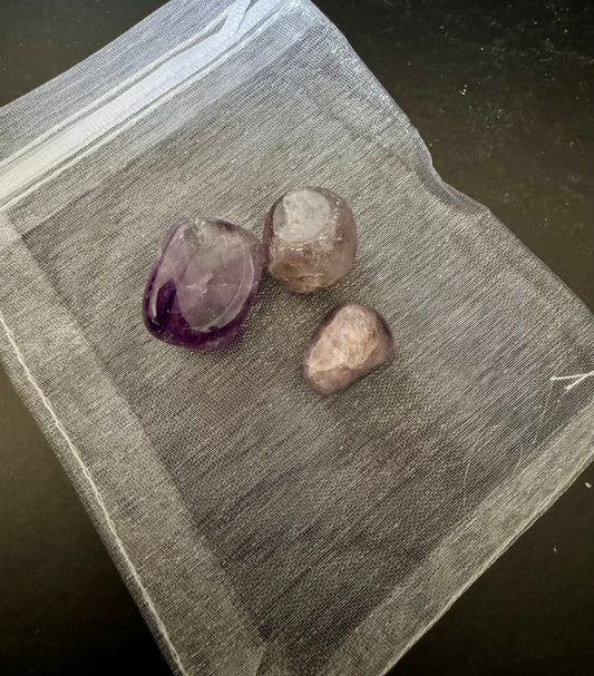 Three amethyst crystals on a textured surface