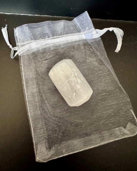 Selenite on a clear drawstring bag on a dark surface